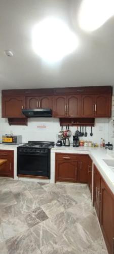 a kitchen with wooden cabinets and a black stove at Casa de huéspedes Chukum in Mexico City