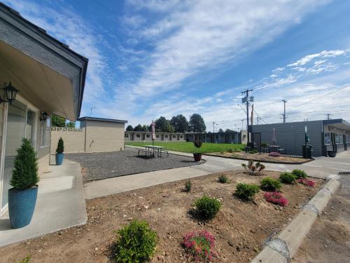 a building with a patio and a park with flowers at Othello Inn And Suites in Othello