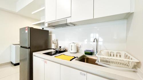 a kitchen with white cabinets and a stainless steel refrigerator at Tulip Residences by Manhattan Group in Shah Alam