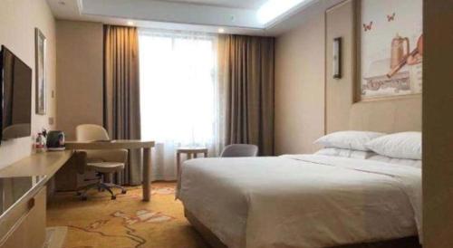 a bedroom with a bed and a desk and a window at Vienna Hotel Zhejiang Tongxiang Puyuan in Jiaxing