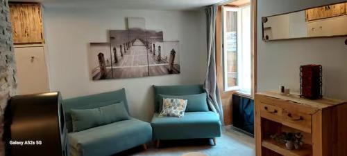 un salon avec un canapé bleu et une photo d'un pont dans l'établissement Studio au cœur de jausiers, à La Celle-sous-Gouzon