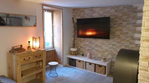 un salon avec une télévision sur un mur en pierre dans l'établissement Studio au cœur de jausiers, à La Celle-sous-Gouzon