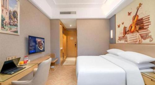 a hotel room with a bed and a desk with a laptop at Vienna Hotel Jiangsu Zhangjiagang Passenger Terminal Station in Zhangjiagang