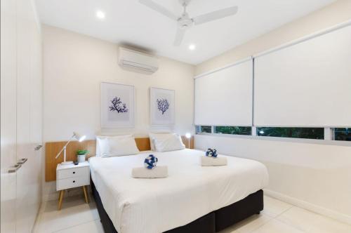 a white bedroom with a large bed and a window at Pool Resort Port Douglas in Port Douglas
