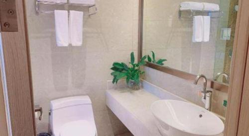 a white bathroom with a toilet and a sink at Vienna Hotel Zhejiang Lishui Qingtian Post Building in Lishui