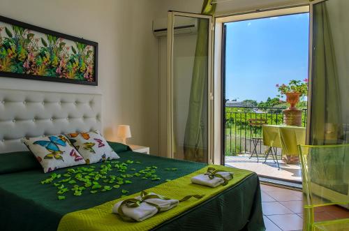 1 dormitorio con 1 cama con zapatillas y balcón en B&B La Stella di Naxos, en Giardini Naxos