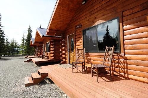 a wooden cabin with two chairs and a large window at Moose-AKa's Cabins in Healy