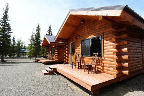 a log cabin with two chairs on a deck at Moose-AKa's Cabins in Healy