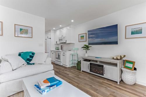 a white living room with a couch and a kitchen at Gorgeous Beach Condo with Private Patio #134 in Carpinteria