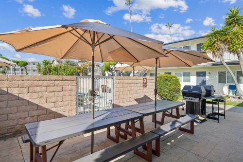 two picnic tables with an umbrella and a grill at Gorgeous Beach Condo with Private Patio #134 in Carpinteria