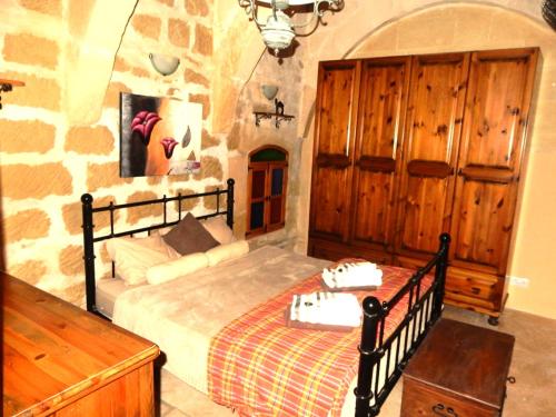 a bedroom with a bed and a stone wall at Tas-Suplu Farmhouse in San Lawrenz