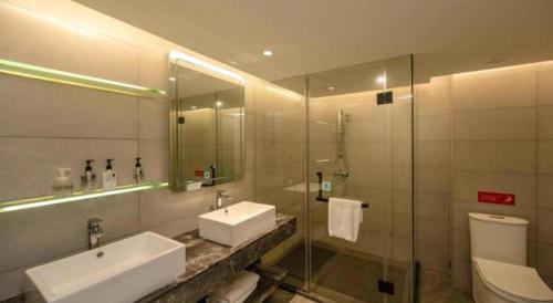 a bathroom with a sink and a toilet and a shower at Echarm Hotel Zhanjiang Zhanchuan Avenue Wanda Plaza in Zhanjiang