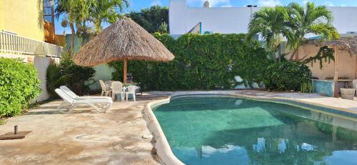 a small swimming pool with a straw umbrella and chairs at Oasis del Mar- Departamento Mar in Progreso