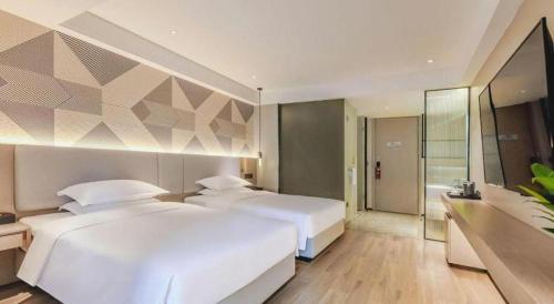 two white beds in a bedroom with a wall at Borrman Hotel Chongqing Bishan Central Street in Chongqing