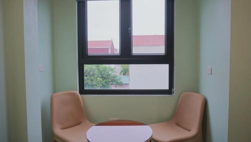 a room with two chairs and a table and a window at Jademay Airport Hotel in Sóc Sơn