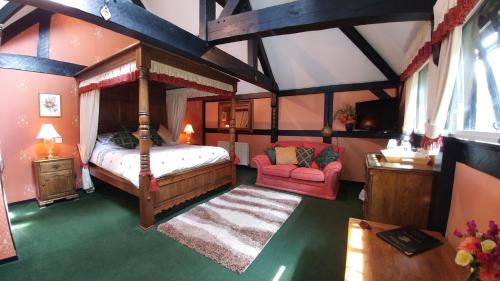 een slaapkamer met een hemelbed en een rode bank bij The Old Priory B&B in Bognor Regis