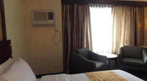 a hotel room with a bed and a chair and a window at MO2 Westown Hotel San Juan in Bacolod