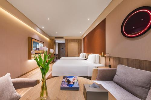 上海Shanghai Hongqiao Hub Minbei Road Orange Crystal Hotel的一间配有床、沙发和桌子的酒店房间