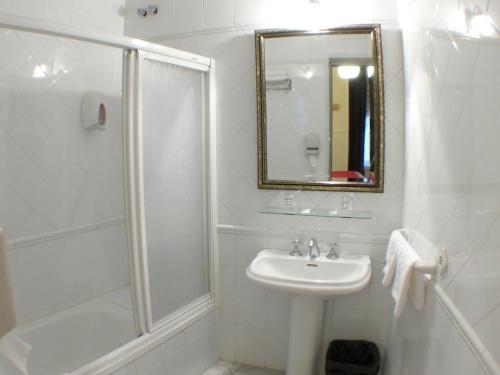 a white bathroom with a shower and a sink at Hostal Canovas in Cuenca