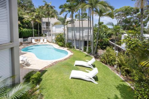 a yard with two lawn chairs and a swimming pool at Noosa Blue Resort in Noosa Heads