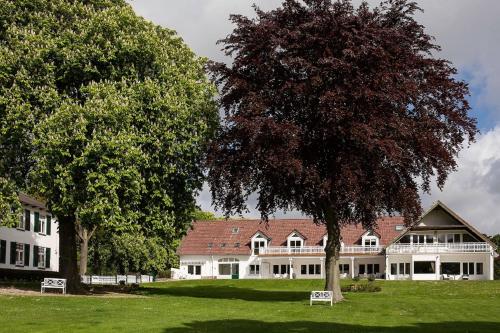 - un grand bâtiment blanc avec un arbre dans la cour dans l'établissement Seehof, à Sierksdorf