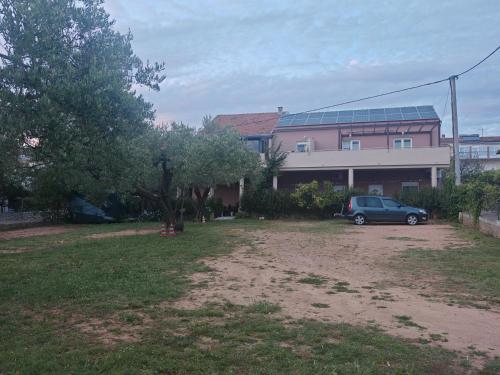 a car parked in a yard next to a building at Apartmani Milat in Sveti Filip i Jakov