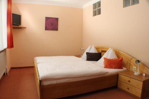 a bedroom with a bed with white sheets and orange pillows at Gasthof zur Bruthenne in Weissenbach an der Triesting