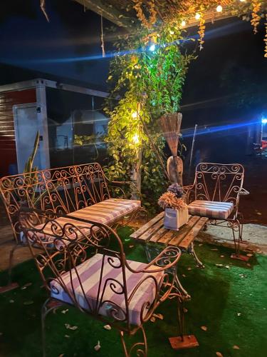 two chairs and a bench in a yard at night at Iglú Sparrow vista al cielo in Barra de Navidad