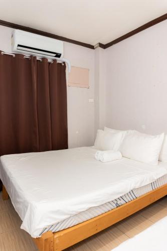 a bed with white sheets and pillows in a room at Townes Huge Home Big Grps Big Fam Near SM Ecoland DGT Coastal road ADDU UM in Davao City