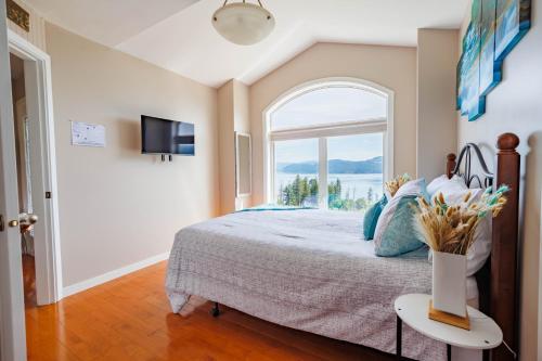 a bedroom with a large bed with a window at Panoramic Acres B & B - Lake & Mountain Views in Vernon