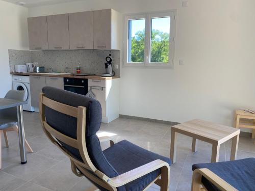 a kitchen with a table and a chair and a table at La maison dans la prairie fleurie, espace et calme in Saint-Avit-Sénieur