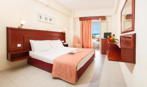 a hotel room with a bed and a balcony at Xenios Loutra Village Beach Hotel in Agia Paraskevi