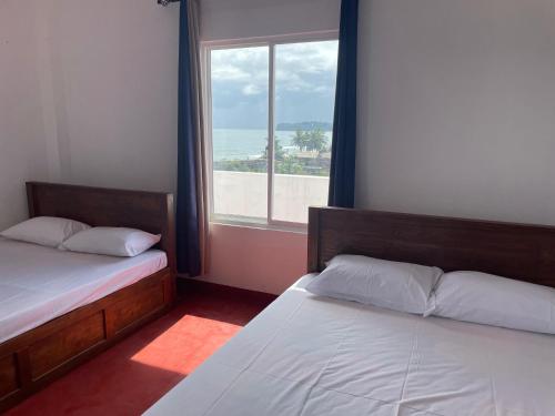亭可马里Trinco Star Hotel的有窗户的房间里有两张床