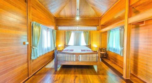 a bedroom with a bed in a room with wooden walls at Burann Bangtanode in Ratchaburi