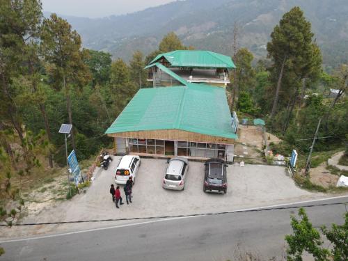 a building with cars parked in a parking lot at Veshnavi Paradise By StayApart in Kausani