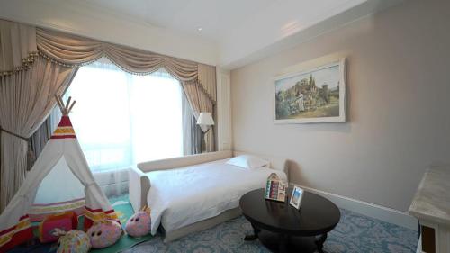 a bedroom with a bed and a table and a window at The Castle Hotel, a Luxury Collection Hotel, Dalian in Dalian