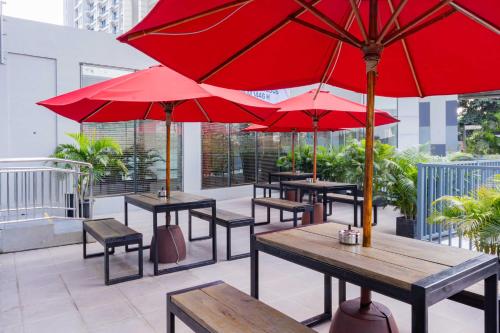 a group of tables with red umbrellas on a patio at Harris Suites Puri Mansion in Jakarta