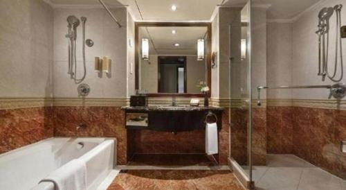 a bathroom with a tub and a sink and a mirror at New Century Hotel Taizhou 