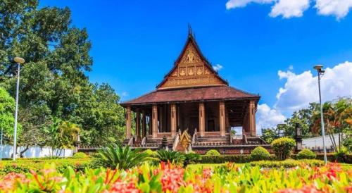 a pagoda in a park with flowers in the foreground at Jian Guo Grand Hotel in Vientiane
