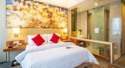a bedroom with a large bed with a painting on the wall at Jinjiang Metropolo Hotel - Taizhou Wanda Plaza in Taizhou