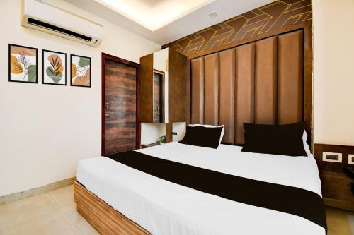 a bedroom with a large bed with a wooden headboard at Hotel O Drishti Grand in Lucknow