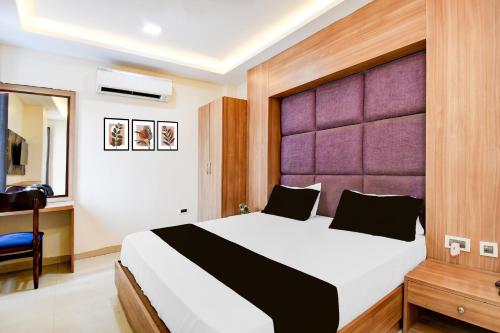 a bedroom with a large bed with a purple headboard at Hotel O Drishti Grand in Lucknow