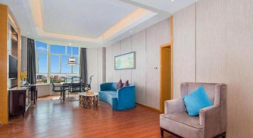 a living room with a blue couch and a chair at Metropolo Hotel Yining Development Zone Hanma Building in Kipekyüzi