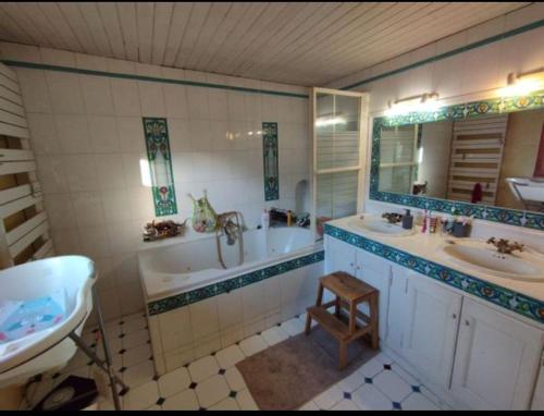 La salle de bains est pourvue de 2 lavabos, d'une baignoire et d'un lavabo. dans l'établissement Au bonheur des petits et grands, à Saint-Quentin-la-Poterie