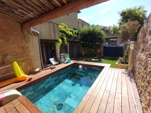une petite piscine avec une terrasse en bois et une maison dans l'établissement Au bonheur des petits et grands, à Saint-Quentin-la-Poterie