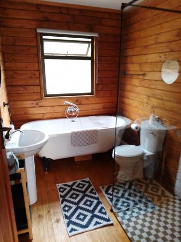 a bathroom with a tub and a toilet and a sink at Tierhoek Cottages in Robertson