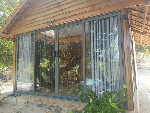 a screened in porch with glass doors and a plant at The Sunrise Anh Tu in Cam Ranh