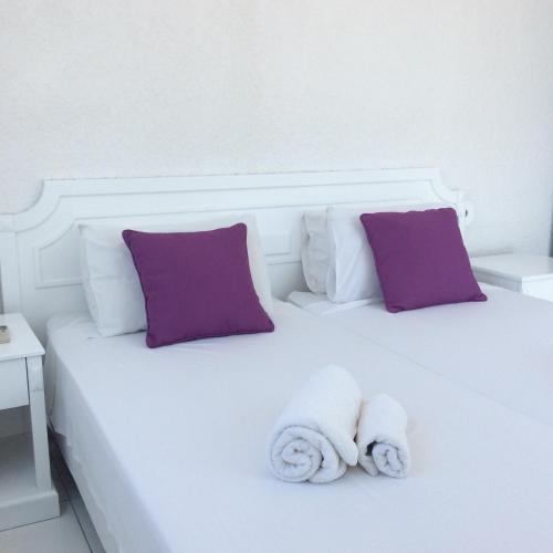 a white bed with purple pillows and towels on it at Aphentrika Apartments in Protaras