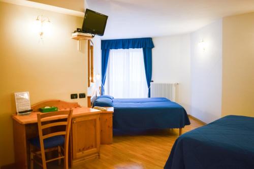 um quarto com 2 camas, uma secretária e uma televisão em Hotel Abete Bianco em Andalo
