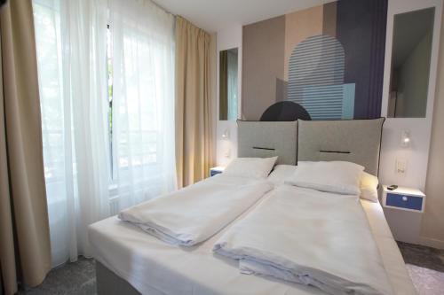 a bedroom with a bed with white sheets and a window at VacationClub - Młyńska 10A Apartament 205 in Kołobrzeg